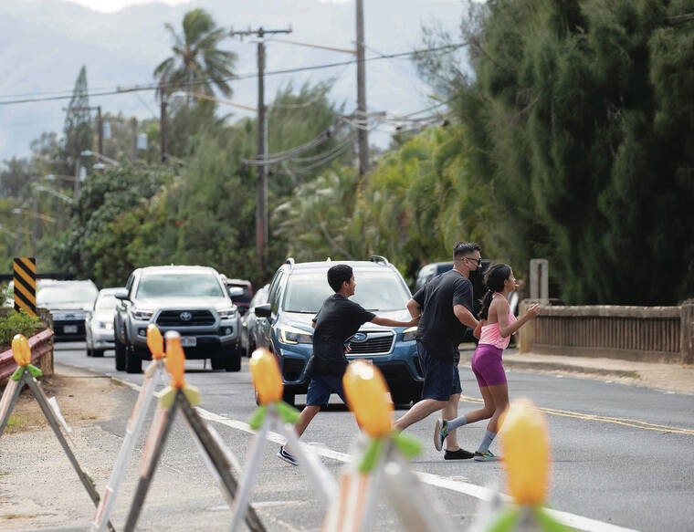 CINDY ELLEN RUSSELL / CRUSSELL@STARADVERTISER.COM
                                People crossed the road Friday to get to Laniakea, or Turtle Beach.