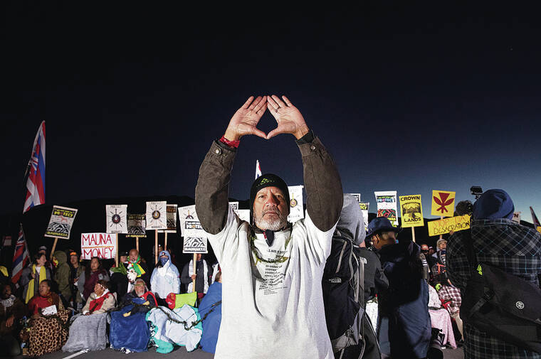 CINDY ELLEN RUSSELL / JULY 2019
                                Dexter Kaiama held his hands high as a tribute to Mauna Kea before a line of kupuna who formed a human barricade in 2019 to stop construction of the Thirty Meter Telescope.