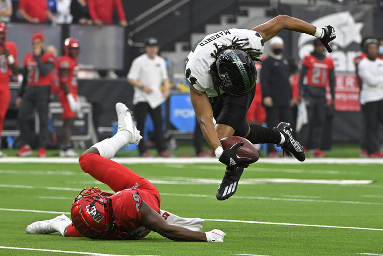 ASSOCIATED PRESS Hawaii wide receiver Nick Mardner breaks a tackle attempt by UNLV defensive back Aaron Lewis during the first half of an NCAA college football game on Saturday in Las Vegas.