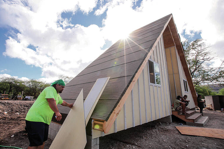 JAMM AQUINO / JAQUINO@STARADVERTISER.COM
                                James Pakele, president of Dynamic Community Solutions, moves panels outside the newly built house at the mauka village in Waianae Valley. Puuhonua o Waianae cleared 20 acres it acquired in March 2020 and built its first new permanent house, a duplex with two A-frames. It plans to build 80 duplexes in the valley, clean up the makai camp and move everyone up to the permanent housing.