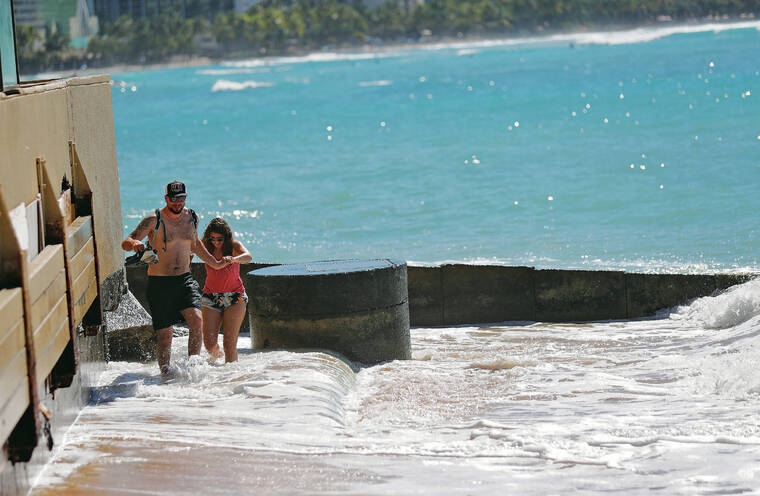 JAMM AQUINO / JAQUINO@STARADVERTISER.COM
                                Waikiki stakeholders have asked Gov. David Ige to declare the area of Waikiki Beach in front of the Outrigger Reef hotel a disaster area. Above, Adriano Coretti, left, and Melinda Pinto, visiting from Switzerland, crossed an inundated Kawehewehe Beach walkway.