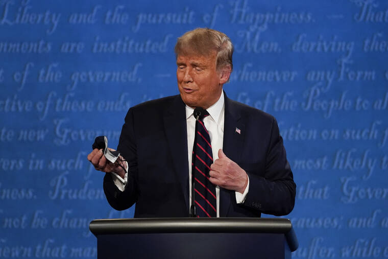 ASSOCIATED PRESS / SEPT. 29, 2020
                                President Donald Trump looks at his face mask during the first presidential debate at Case Western University and Cleveland Clinic, in Cleveland, Ohio, on Sept. 29. 2020. A book by Donald Trump’s ex-chief of staff says Trump tested positive for COVID-19 three days before his first debate in September 2020.