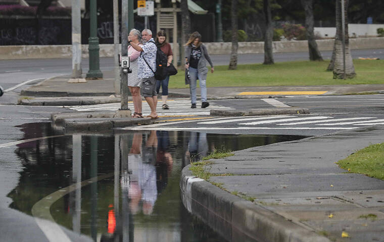 JAMM AQUINO / JAQUINO@STARADVERTISER.COM
                                Pedestrians were reflected in floodwaters on Oahu Monday. Heavy rain and high winds pounded much of the state due to the lingering Kona low system south of the islands.