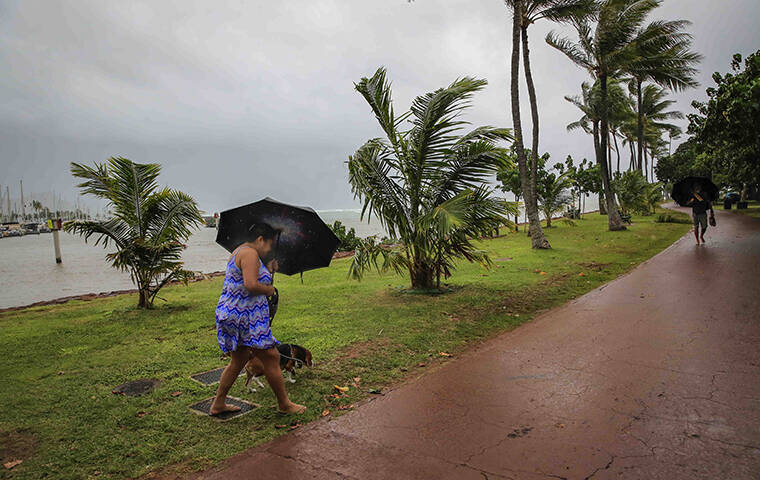 JAMM AQUINO / JAQUINO@STARADVERTISER.COM
                                A woman walks her dog in high wind and rain today at Ala Moana Regional Park in Honolulu.