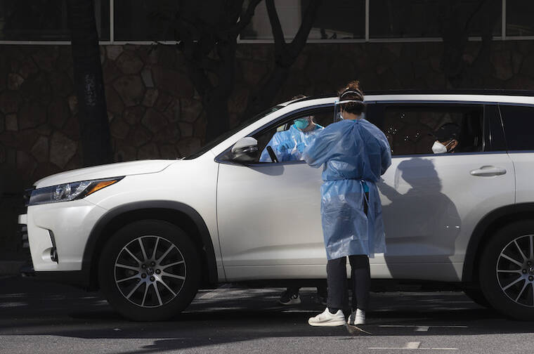 CINDY ELLEN RUSSELL / DEC. 24 Health care workers administer COVID-19 tests at the free drive thru and walk-up vaccination clinic set up at Neal S. Blaisdell parking lot.