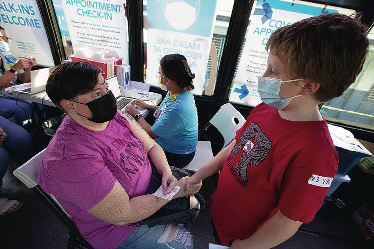 GEORGE F. LEE / GLEE@STARADVERTISER.COM
                                Lori Case held her son Samson’s hand as she waited to receive a shot at a Hawaii Pacific Health mobile COVID-19 vaccination clinic held at Red Hill Elementary School on Wednesday.