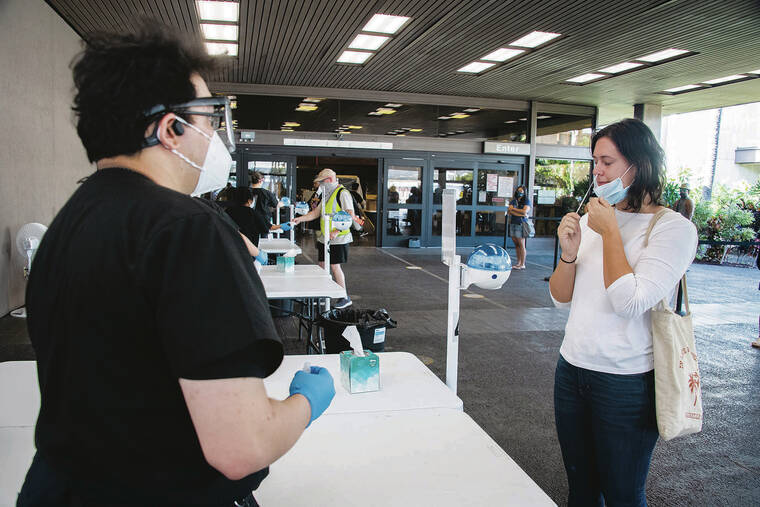 CRAIG T. KOJIMA / CKOJIMA@ STARADVERTISER.COM
                                Alex Santos waited Saturday as Haley Trumbo swabbed for a COVID-19 test at Daniel K. Inouye International Airport. About 50 people were lined up Saturday afternoon at the airport testing site, which administered 1,192 tests that day, compared with about 500 tests on a typical day before the omicron variant was detected in Hawaii on Dec. 2.