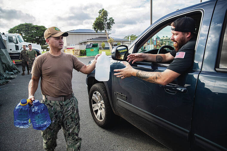 CINDY ELLEN RUSSELL / CRUSSELL@STARADVERTISER.COM
                                Navy Chief Petty Officer Thinh Le handed a gallon jug of water to Kevin Mulloy on Thursday at Halsey Terrace Community Center. By mid­afternoon 700 gallons of water had been distributed to military families affected by the Red Hill water contamination crisis.