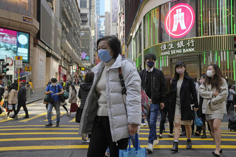 ASSOCIATED PRESS People walked across a street in Hong Kong, Tuesday. Passengers who have stayed in over 150 places deemed high risk in the last 21 days, including the United States and Britain, will be banned from transiting in Hong Kong from Jan. 16 to Feb. 15, according to a notice posted by the airport.