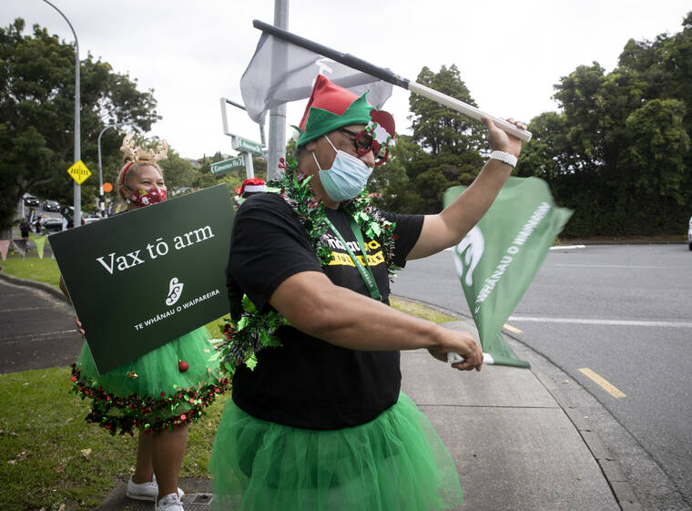 DEAN PURCELL/NEW ZEALAND HERALD VIA ASSOCIATED PRESS
                                Mona Lisa, left, and Tau Apihai performed along the roadside to encourage people to get vaccinated, Dec. 21, in Auckland, New Zealand. New Zealand is among the few remaining countries to have avoided any outbreaks of the omicron variant — but Prime Minister Jacinda Ardern said Thursday an outbreak was inevitable and the nation would tighten restrictions as soon as one was detected.