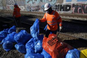 ASHLEY LANDIS / AP
                                Workers bag cardboard and other discarded items at a Union Pacific railroad site on Thursday in Los Angeles.