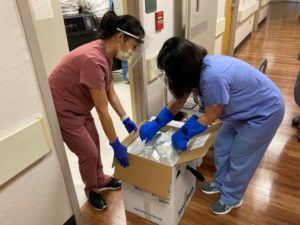 COURTESY THE QUEEN’S MEDICAL CENTER
                                Queen’s Medical Center staffers unpack a box filled with doses of COVID-19 vaccine.