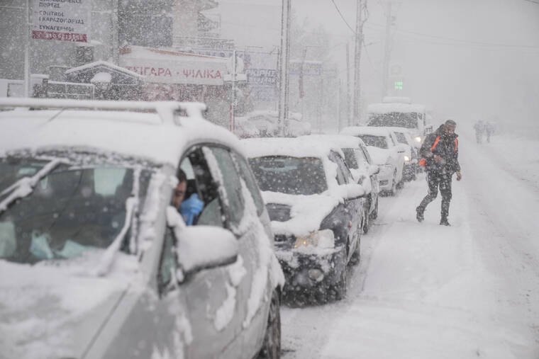 ASSOCIATED PRESS
                                Vehicles drive as a man cross a street during snowfall in Agios Steganos, north of Athens. The wave of bad weather hitting Greece is forecast to continue through Tuesday, and has seen snow falling even on some islands. Authorities have warned the public to avoid all but essential outdoor movement, and several major roads and highways are passable only with snow chains.