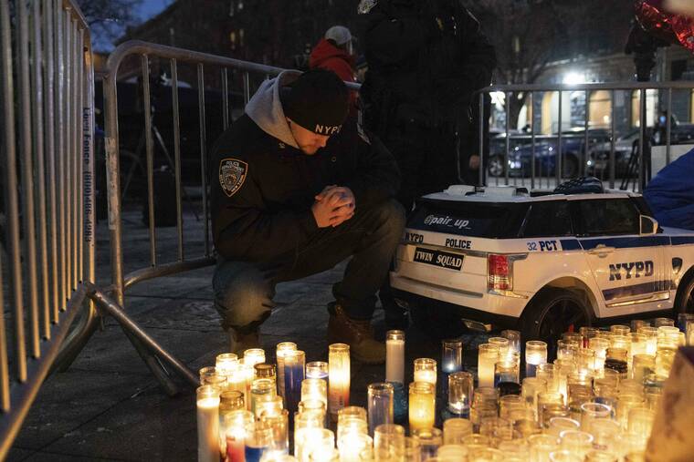 ASSOCIATED PRESS
                                A police officer prayed at a makeshift memorial outside the New York City Police Department’s 32nd Precinct, near the scene of a shooting days earlier in the Harlem neighborhood of New York, Monday.