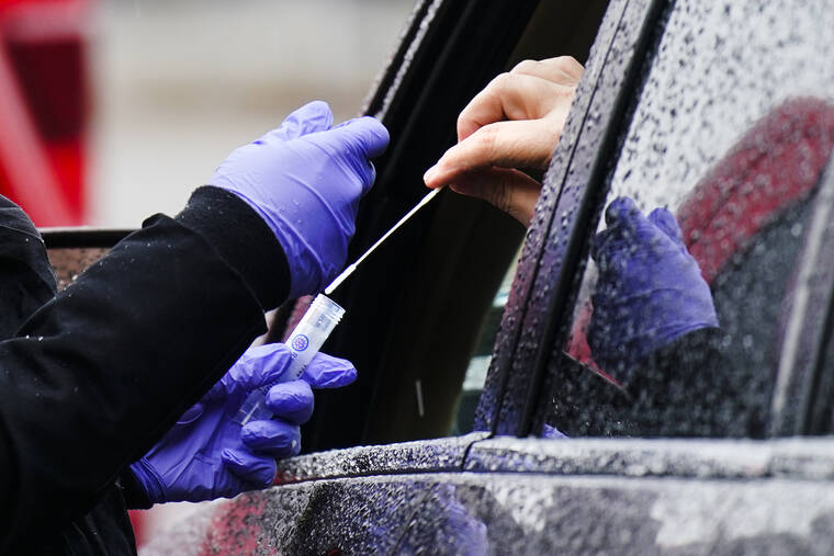 ASSOCIATED PRESS
                                A driver placed a swab into a vial at a free drive-thru COVID-19 testing site in the parking lot of the Mercy Fitzgerald Hospital in Darby, Pa., Jan. 20. A requirement to get vaccinated against COVID-19 kicks in Thursday for millions of health care workers in about half the states.