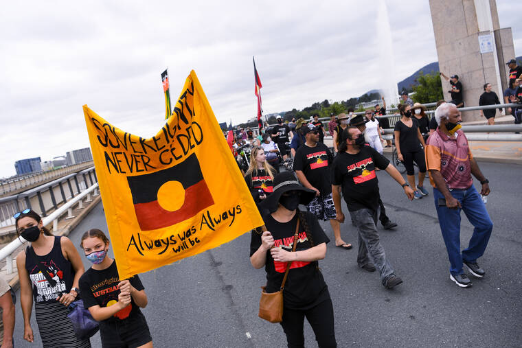 AAP IMAGE VIA AP
                                Protesters hold placards as they march during a protest marking the 50th anniversary of the the Aboriginal Embassy, in Canberra, Australia, today.