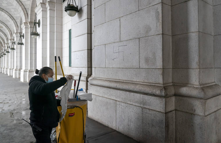 J. SCOTT APPLEWHITE / AP
                                A worker prepares to cover hand-drawn swastikas on the front of Union Station near the Capitol in Washington.
