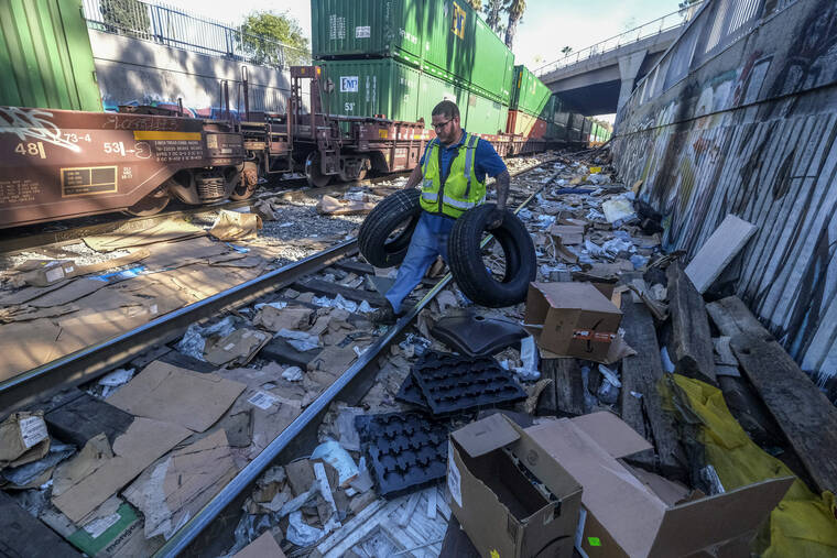 ASSOCIATED PRESS
                                Contractor worker Adam Rodriguez recovers vehicle tires from the shredded boxes and packages along a section of the Union Pacific train tracks in downtown Los Angeles on Jan. 14. Authorities say dozens of handguns and shotguns were among items stolen by thieves who raided cargo containers aboard trains near downtown Los Angeles for months.