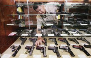 CINDY ELLEN RUSSELL / CRUSSELL@STARADVERTISER.COM
                                Young Guns salesman reached into a handgun case at the Mapunapuna store.