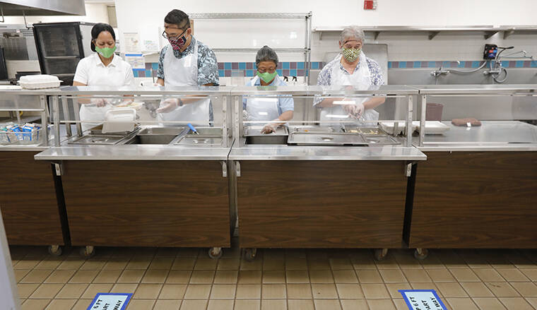 STAR-ADVERTISER / 2020
                                Cafeteria staff prepare lunch as social distancing signage is seen on the ground inside the cafeteria on Thursday, July 2, at Kapolei Middle School in Kapolei.