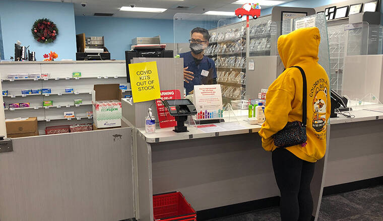 ASSOCIATED PRESS / JAN. 4 A woman waits at the pharmacy counter at a CVS on Sunset Boulevard in the Echo Park neighborhood of Los Angeles where the location is sold out of CIOVID at-home rapid test kits during the omicron surge.