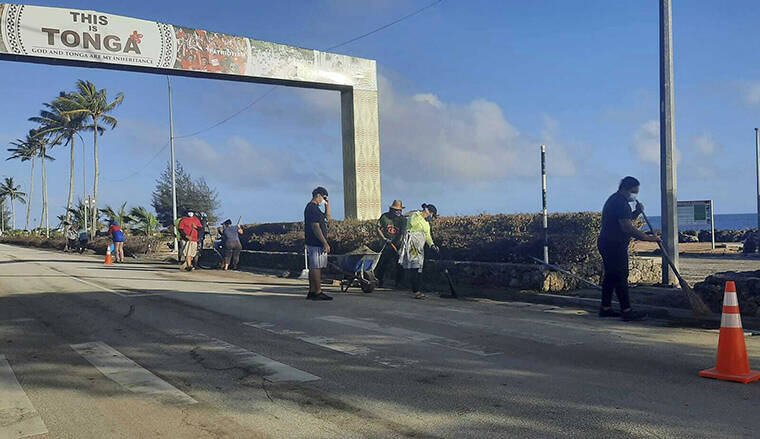 BROADCOM BROADCASTING / AP
                                People clear debris off the street in Nuku’alofa, Tonga, on Thursday.