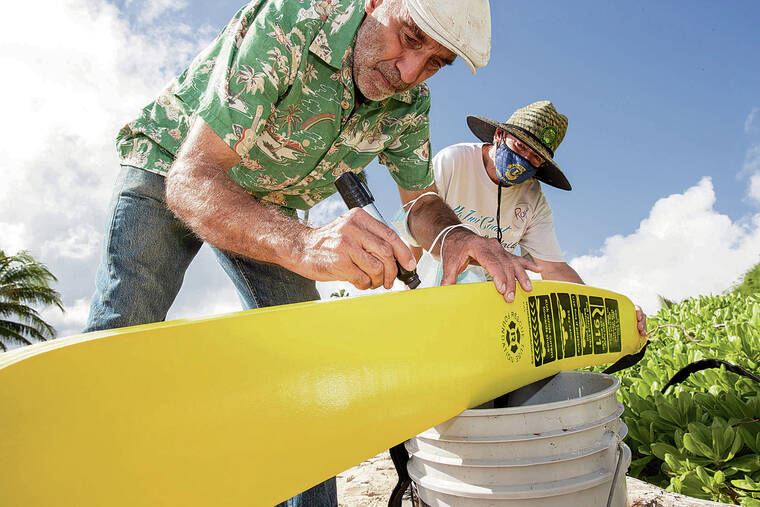CINDY ELLEN RUSSELL / CRUSSELL@STARADVERTISER.COM
                                Above, resident Patrick Steinemann — who spearheaded the project — writes “For Emergency Use Only” on a rescue tube while Kern looks on.