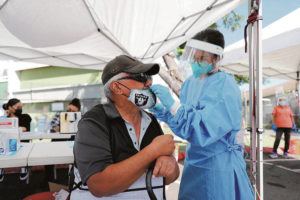 JAMM AQUINO / JAQUINO@STARADVERTISER.COM
                                Project Vision Hawaii medical assistant Angelica Bagaoisan, right, performed a COVID-19 antigen test Thursday on Salt Lake resident Charles Wahinehookai during a vaccination and testing clinic at Palama Settlement.