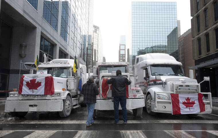 THE CANADIAN PRESS / AP
                                Truck drivers hang a Canadian flag on the front grill of a truck parked in downtown Ottawa, Ontario, near Parliament Hill.