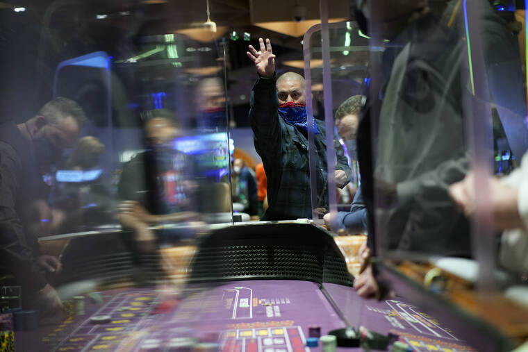 ASSOCIATED PRESS / MARCH 25
                                People play craps while wearing masks and between plexiglass partitions as a precaution against the coronavirus at the opening night of the Mohegan Sun Casino at Virgin Hotels Las Vegas in Las Vegas. Nevada and its casinos have rescinded requirements for people to wear masks in public, joining most other U.S. states lifting restrictions that were imposed to limit the spread of the coronavirus. Democratic Gov. Steve Sisolak announced Thursday, Feb. 10, that he would no longer require face coverings in public places, “effective immediately.”