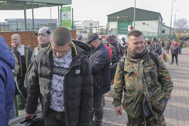 ASSOCIATED PRESS
                                Polish volunteer Jedrzej, 34, in military uniform joins Ukranians, left, waiting to cross the border to go and fight against Russian forces, at Medyka border crossing in Poland on Saturday.