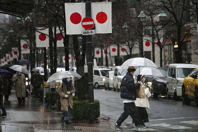 ASSOCIATED PRESS / FEB. 10 People wearing protective masks to help curb the spread of the coronavirus walk on the street in snow in Tokyo.