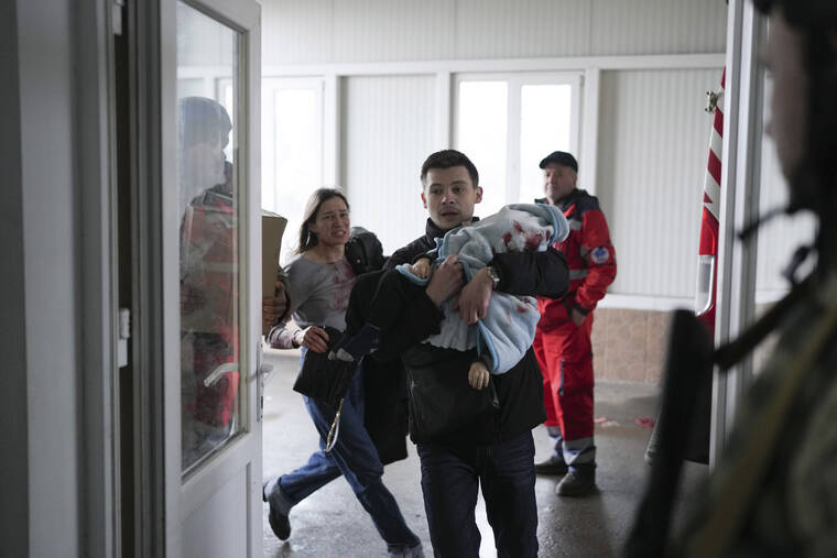 ASSOCIATED PRESS / MARCH 4
                                Marina Yatsko, left, runs behind her boyfriend Fedor carrying her 18 month-old son Kirill who was killed in shelling, as they arrive at a hospital in Mariupol, Ukraine.