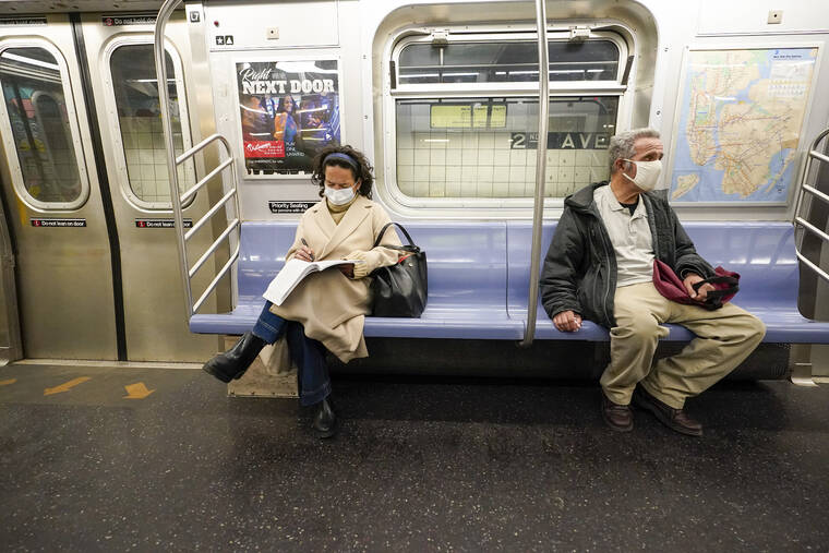 ASSOCIATED PRESS Commuters wear face masks and social distance while riding an M Train Tuesday in New Yorks subway system.
