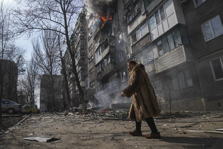 ASSOCIATED PRESS
                                A woman walked past a burning apartment building after shelling in Mariupol, Ukraine, Sunday.