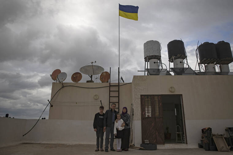 ASSOCIATED PRESS
                                Ukrainian Oksana al-Astal stands with her Palestinian husband and their children as they pose for a photo as a Ukrainian flag waves over the roof top of their home in Khan Younis in the southern Gaza Strip.