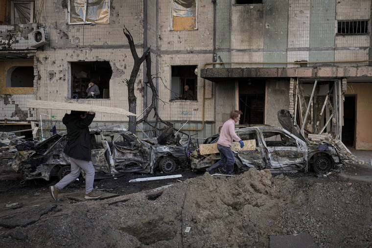 ASSOCIATED PRESS
                                People carried wooden boards to cover the windows of a building damaged by a bombing the previous day in Kyiv, Ukraine, today. As Russia intensified its effort to pound Mariupol into submission, its ground offensive in other parts of Ukraine has become bogged down.