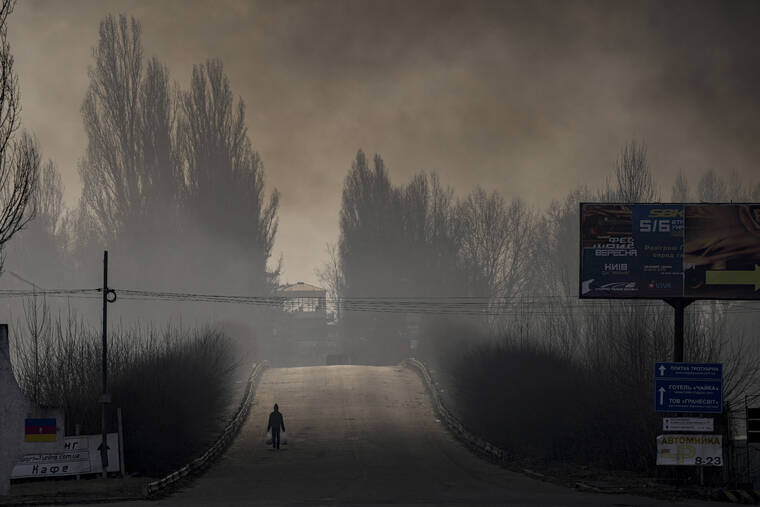 ASSOCIATED PRESS
                                A man carried shopping bags as heavy smoke from a warehouse destroyed by Russian bombardment casted shadows on the road outside Kyiv, Ukraine, today. Ukraine President Volodymr Zelenskyy called on people worldwide to gather in public today to show support for his embattled country as he prepared to address President Joe Biden and other NATO leaders gathered in Brussels on the one-month anniversary of the Russian invasion.