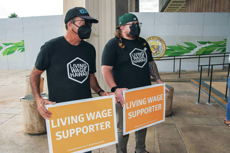 CRAIG T. KOJIMA / CKOJIMA@STARADVERTISER.COM
                                Sign holders were at the state Capitol on Tuesday to push for raising the state’s minimum wage. The Living Wage Rally was organized by Raise Up Hawaii, a coalition of businesses, advocacy organizations, labor unions and nonprofits advocating for an increase. Pictured are Tony Samuels, left, a part-time worker, and Aaron Sansone, a University of Hawaii student.