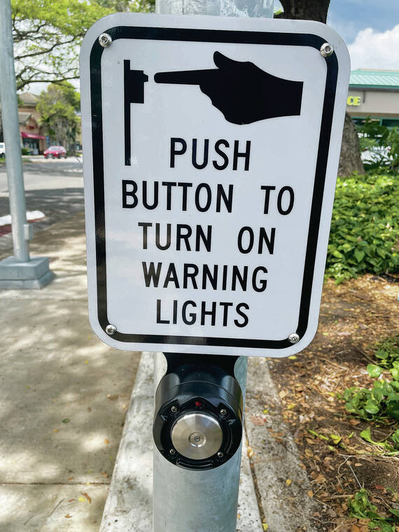 NINA WU / 
NWU@STARADVERTISER.COM
                                To activate the flashing beacon, pedestrians and bicyclists push a button to alert motorists of their need to cross.