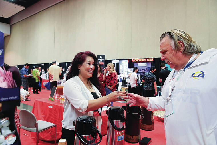 JAMM AQUINO / JAQUINO@STARADVERTISER.COM
                                Shawn Mawae, left, with Lion Coffee, handed a sample to Scott Rhine during the first day of the 2022 Hawai‘i Hotel & Restaurant Show on Wednesday at the Hawai‘i Convention Center.
