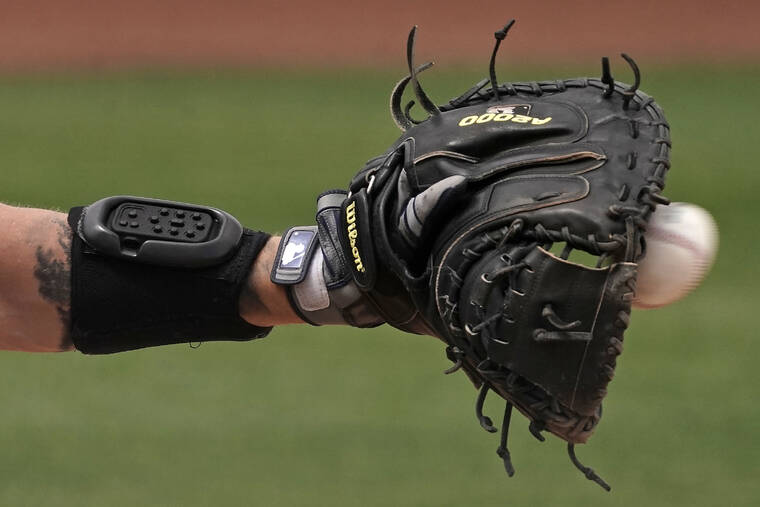 ASSOCIATED PRESS
                                Seattle Mariners catcher Tom Murphy wears a wrist-worn device used to call pitches as he catches a ball during the sixth inning of a spring training baseball game against the Kansas City Royals on March 29 in Peoria, Ariz. The MLB is experimenting with the PitchCom system where the catcher enters information on a wrist band with nine buttons which is transmitted to the pitcher to call a pitch.