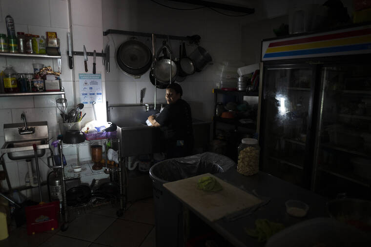 CARLOS GIUSTI / AP
                                Workers at Las Palmas Cafe work with the power of an electricity generator during an island-wide blackout, in San Juan, Puerto Rico, Thursday.