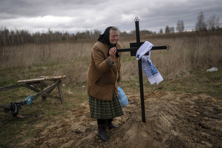 RODRIGO ABD / AP
                                Nadiya Trubchaninova, 70, cries while holding the cross of her son Vadym, 48, who was killed by Russian soldiers last March 30 in Bucha, during his funeral in the cemetery of Mykulychi, on the outskirts of Kyiv, Ukraine, Saturday.
