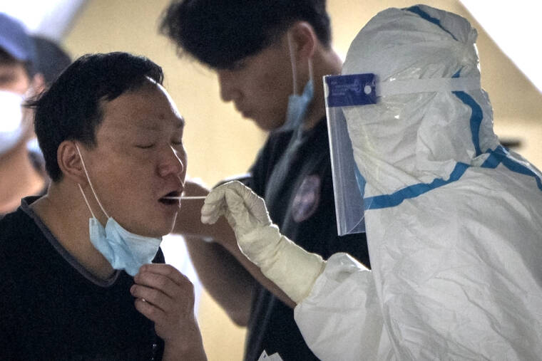 MARK SCHIEFELBEIN / AP
                                A worker in a protective takes a swab for a COVID-19 test at a coronavirus testing facility in Beijing.