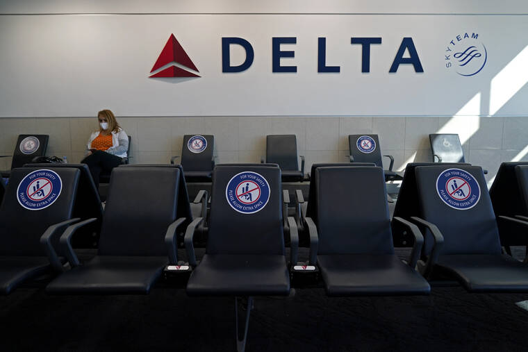 ASSOCIATED PRESS A passenger wore a face mask as she waited in a socially-distanced area for a Delta Airlines flight, in February 2021, at Hartsfield-Jackson International Airport in Atlanta. Delta Air Lines will start paying flight attendants during the time that passengers are boarding.