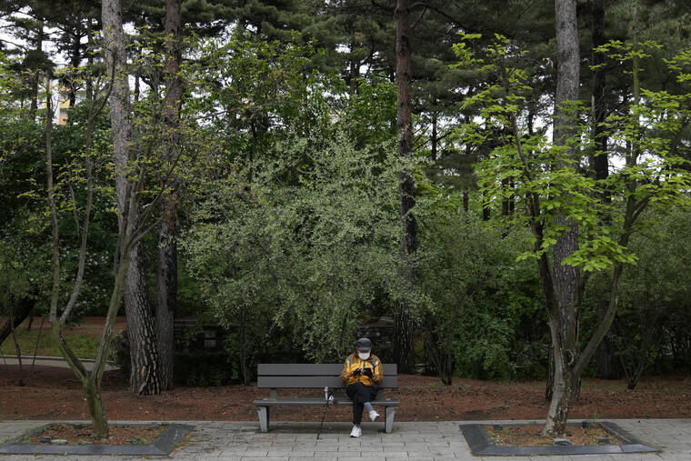 ASSOCIATED PRESS
A man wearing a face mask to help curb the spread of the coronavirus sits on a bench while maintaining social distancing at a park in Seoul, South Korea.
