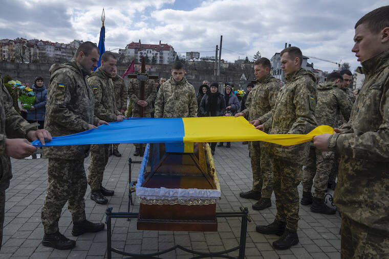 ASSOCIATED PRESS / APRIL 4
                                Soldiers place the Ukrainian flag on the coffin of 41-year-old soldier Simakov Oleksandr, during his funeral ceremony, after after he was killed in action, at the Lychakiv cemetery, in Lviv, western Ukraine.