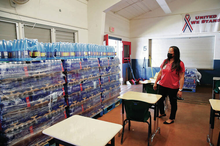 JAMM AQUINO / JAQUINO@STARADVERTISER.COM
                                Above, Red Hill Elementary School Principal Komarey Moss looked Thursday at pallets of bottled water stored inside the school cafeteria.