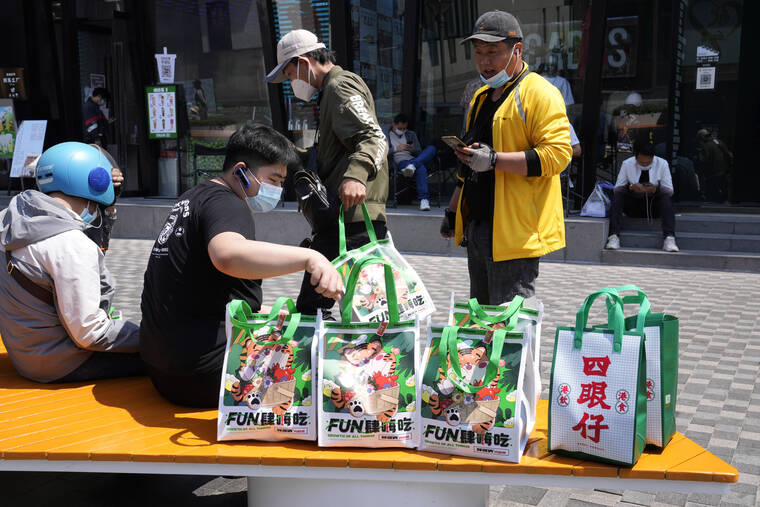 ASSOCIATED PRESS
                                Delivery men collect their orders from a bench outside a mall area in Beijing. All Beijing restaurants were closed to dine-in customers from Sunday and can offer only takeout and delivery through the end of the national holiday on Wednesday.